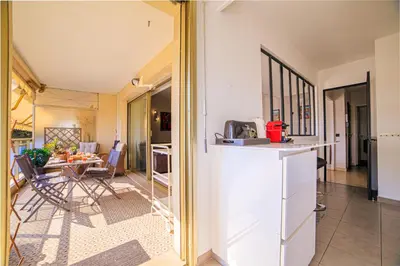 a kitchen and living room with a table and chairs at Le Prado Parc in Cannes
