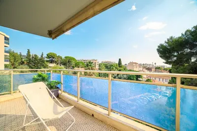 a balcony with a chair and a swimming pool at Le Prado Parc in Cannes