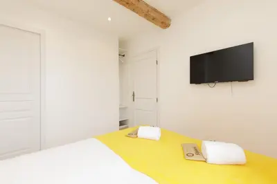 a white bedroom with a bed with a tv on the wall at Great Sea View YourHostHelper in Cannes