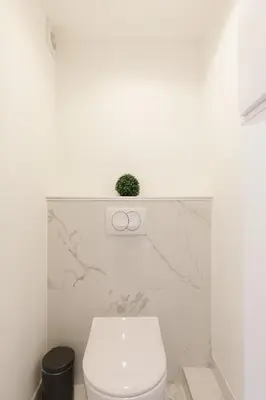 a white bathroom with a toilet and a plant on the wall at Great Sea View YourHostHelper in Cannes
