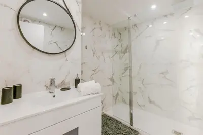 a white bathroom with a sink and a mirror at 90m on the Croisette with Terrace & Sea View in Cannes