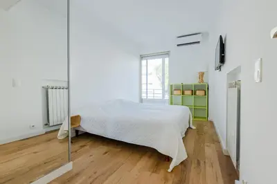 a white bedroom with a bed and a mirror at 90m on the Croisette with Terrace & Sea View in Cannes