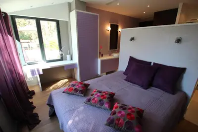 a bedroom with a bed with purple pillows and a window at SUPERBE MAISON DE VILLE in Cannes