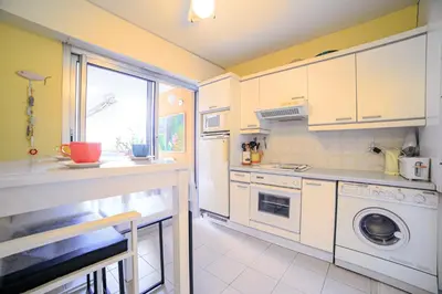 a kitchen with white cabinets and a washer and dryer at Appartement Les Allées in Cannes