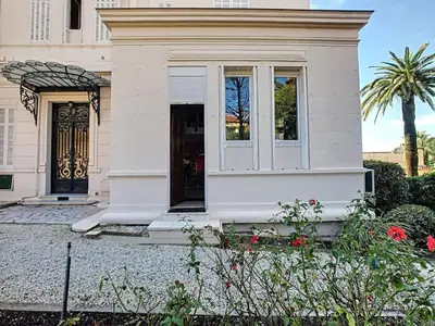 a white house with a front door and flowers at Charmant appartement dans villa avec parc in Cannes