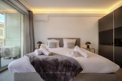 a bedroom with two beds and a large window at Cannes Luxury Rental - Stunning apartment with terrace to rent Grand Hotel in Cannes
