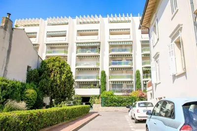 a large white building with cars parked in front of it at Le Bain De Soleil - Le Bain De Soleil 5 star Two bedroom apartment in Cannes