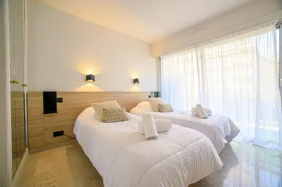 a bedroom with two beds with white sheets and a window at Le Bain De Soleil - Le Bain De Soleil 5 star Two bedroom apartment in Cannes
