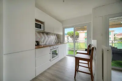 a kitchen with white cabinets and a table and chairs at IMMOGROOM - Terrace - Near shops - Parking - Wifi - AC livingroom in Cannes