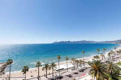 a view of a beach with palm trees and the ocean at Kiss in Cannes