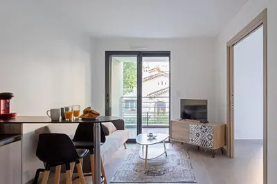 a living room with a table and a television at Appartement Maréchal - Welkeys in Cannes