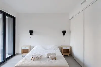a white bedroom with a bed and two night stands at Appartement Maréchal - Welkeys in Cannes