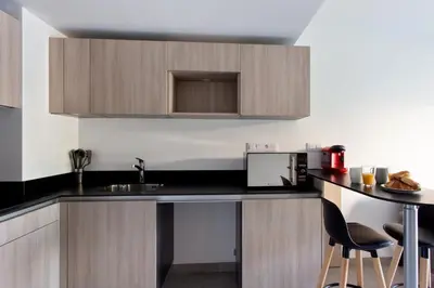 a kitchen with a sink and a counter with chairs at Appartement Maréchal - Welkeys in Cannes