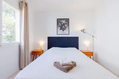 a bedroom with a large white bed with two lamps at 2Br 3 min from the center & the Croisette in Cannes