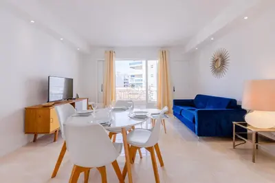 a living room with a table and chairs and a blue couch at 2Br 3 min from the center & the Croisette in Cannes