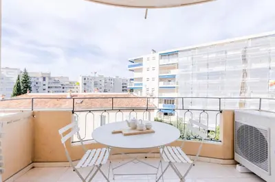 a balcony with a white table and chairs on a building at 2Br 3 min from the center & the Croisette in Cannes