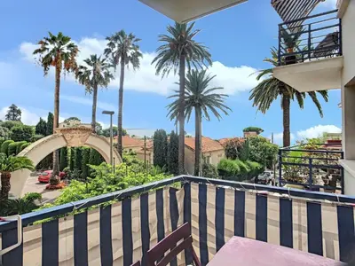 a balcony with a table and palm trees at Appartement charmant à Cannes avec vue sur la mer, 33 m² in Cannes