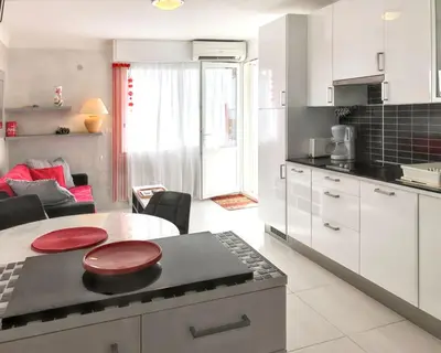 a kitchen with white cabinets and a table with red plates on it at Appartement charmant à Cannes avec vue sur la mer, 33 m² in Cannes