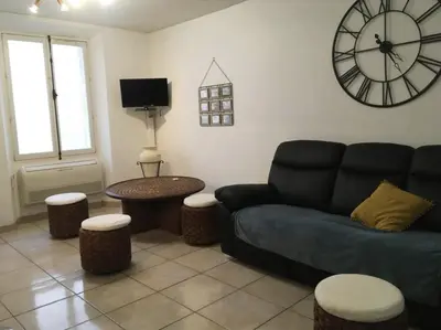 a living room with a couch and a clock on the wall at C087-Comfortable apartment in the heart of Cannes in Cannes