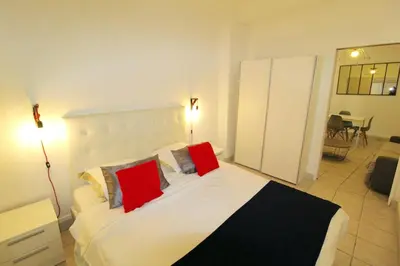 a bedroom with a large white bed with red pillows at Appartement confortable à Cannes avec climatisation - 53 m² in Cannes