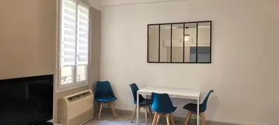 a dining room with a table and blue chairs at Appartement confortable à Cannes avec climatisation - 53 m² in Cannes