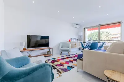 a living room with blue chairs and a flat screen tv at 1-Br Apartment 5 min on foot from the Croisette in Cannes