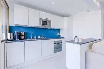 a kitchen with white cabinets and a blue accent wall at 1-Br Apartment 5 min on foot from the Croisette in Cannes