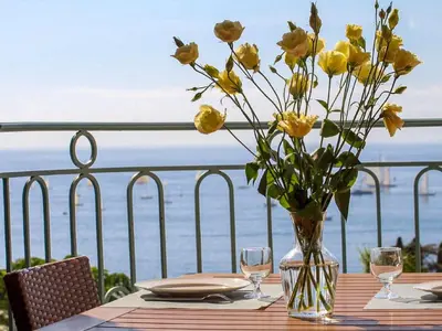 a table with yellow flowers in a vase on a balcony at Apartment Villa Francia-6 by Interhome in Cannes