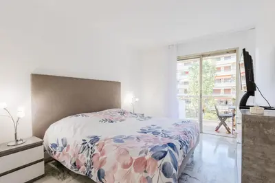 a bedroom with a bed and a large window at Renovated 3-Room Apartment in a Leafy Park in Cannes