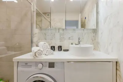 a bathroom with a washing machine and a sink at Renovated 3-Room Apartment in a Leafy Park in Cannes