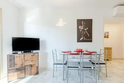 a dining room with a table with chairs and a tv at Renovated 3-Room Apartment in a Leafy Park in Cannes