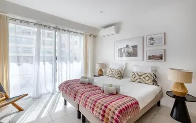 a white bedroom with a large window and a bed at Agence des Résidences - Appartements privés du 45 CROISETTE - Superieur in Cannes