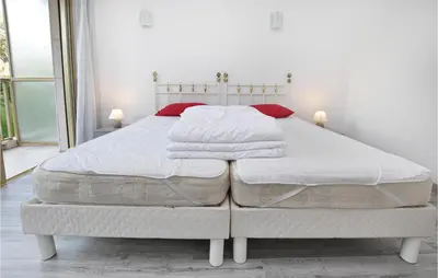 a large white bed with white sheets and red pillows at 1 Bedroom Lovely Apartment In Cannes in Cannes