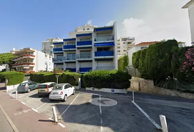 a parking lot with cars parked in front of a building at Le Nouveau Port By SCLS Locations in Cannes