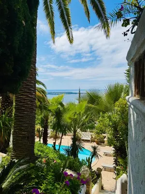 a resort with a pool and palm trees and the ocean at Somptuous exotic villa in Cannes in Cannes
