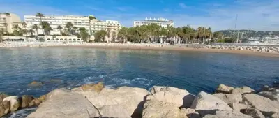 a beach with rocks in the water and buildings at Beau meublé 3 pièces 60 m² Cannes Le Suquet in Cannes