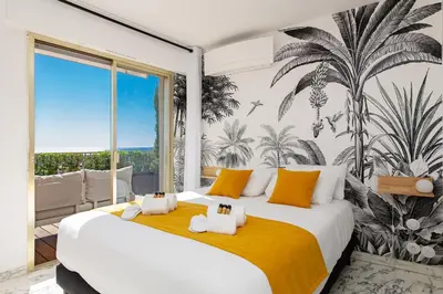 a bedroom with two beds and a palm mural at Rooftop View - 2 BdR 2 BthR 1 toil - Clim Terrace Elevator small Parking in Cannes