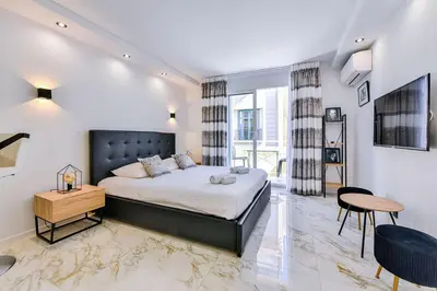 a bedroom with a king sized bed and a table at Large studio - 50m Cannes beach - terrace sea view in Cannes