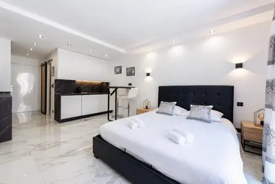 a bedroom with a large white bed and a piano at Large studio - 50m Cannes beach - terrace sea view in Cannes