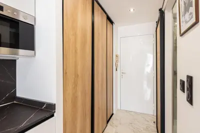 a kitchen with a wooden door and a hallway at Large studio - 50m Cannes beach - terrace sea view in Cannes