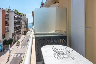 a balcony with a table and a refrigerator on a building at Large studio - 50m Cannes beach - terrace sea view in Cannes