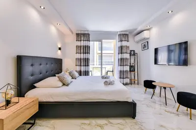 a bedroom with a large bed and a tv at Large studio - 50m Cannes beach - terrace sea view in Cannes