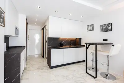 a kitchen with white cabinets and a black counter top at Large studio - 50m Cannes beach - terrace sea view in Cannes
