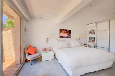 a bedroom with a large white bed and a chair at MAGNIFIQUE VILLA 8 PERSONNES in Vallauris