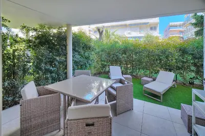 a patio with a table and chairs and an umbrella at IMMOGROOM - Garden - Bikes - BBQ - Parking - AC in Cannes