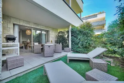an outdoor patio with wicker chairs and a grill at IMMOGROOM - Garden - Bikes - BBQ - Parking - AC in Cannes