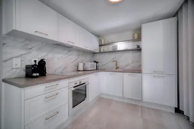 a white kitchen with white cabinets and appliances at IMMOGROOM - Garden - Bikes - BBQ - Parking - AC in Cannes