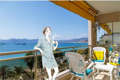 a woman standing on a balcony overlooking the water at On la Croisette XXL 1 bedroom with amazing sea view in Cannes