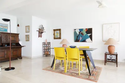 a dining room with a table and yellow chairs at On la Croisette XXL 1 bedroom with amazing sea view in Cannes