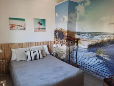a bedroom with a bed with a painting of the beach at Cannes beach and Festival Palais in Cannes